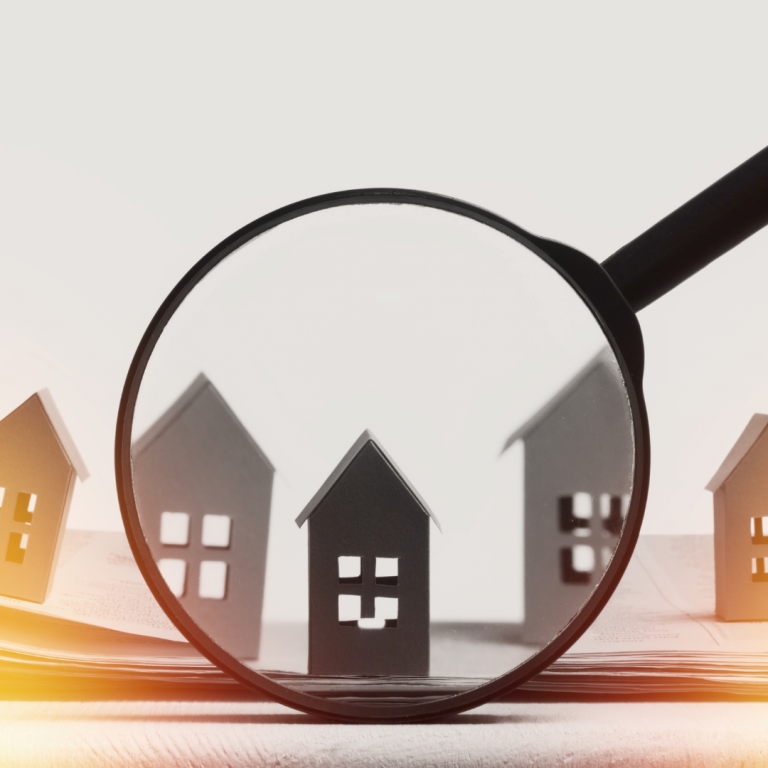 Loupe examinant des maisons en papier, symbolisant un état des lieux d'un bien